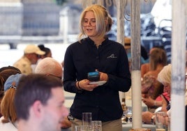 Una camarera de un restaurante de la Plaza Mayor de Segovia atiende a unos comensales en la terraza.