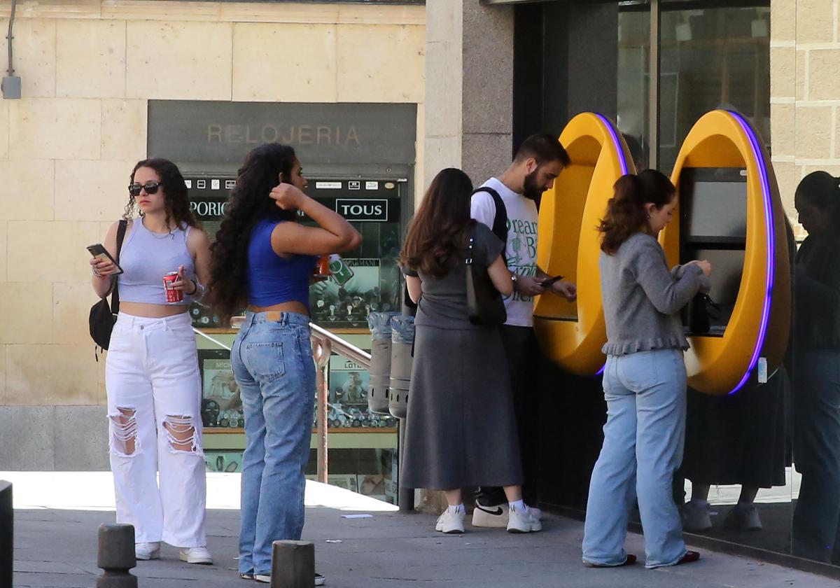 Un grupo de jóvenes saca dinero de unos cajeros automáticos en el centro de Segovia.