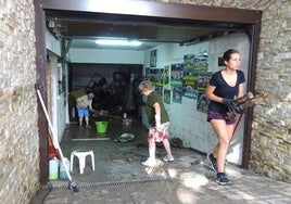 Residentes y familiares sacan los enseres afectados por la tromba que anegó una vivienda de la calle Obispo Barrientos de Medina del Campo.