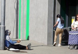 Un hombre pide dinero a las clientas que salen de un supermercado en la capital.