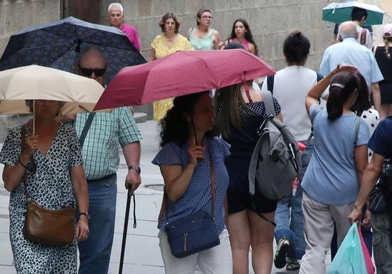 Varias personas se protegen de la lluvia con paraguas en Segovia.