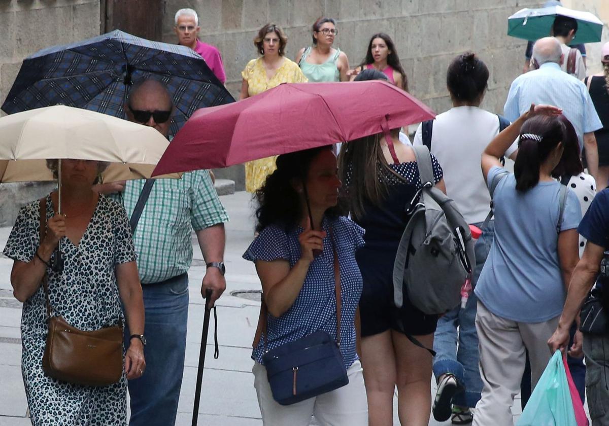 Varias personas se protegen de la lluvia con paraguas en Segovia.