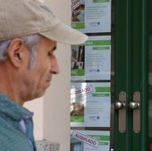 Un hombre pasea junto al escaparate de una inmobiliaria donde se anuncian viviendas en alquiler.
