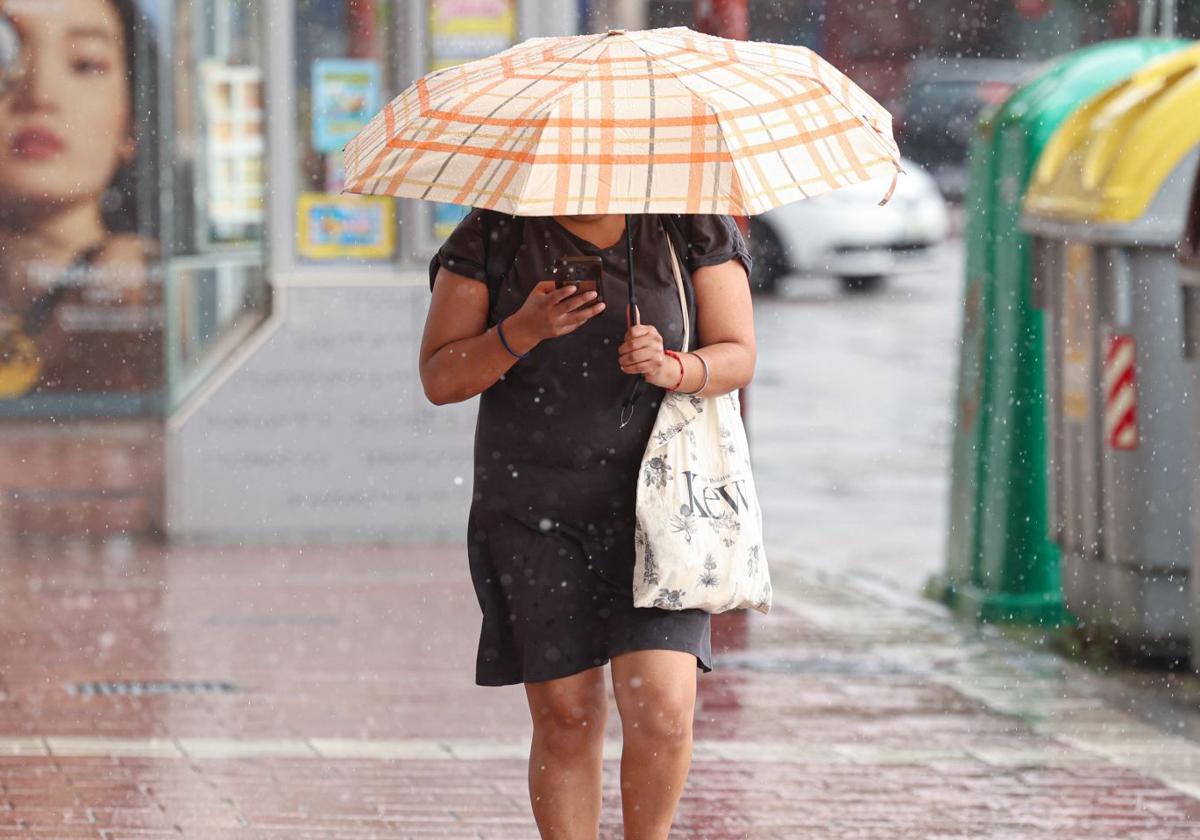 Una mujer se protege de la lluvia en Valladolid, en una imagen de archivo.