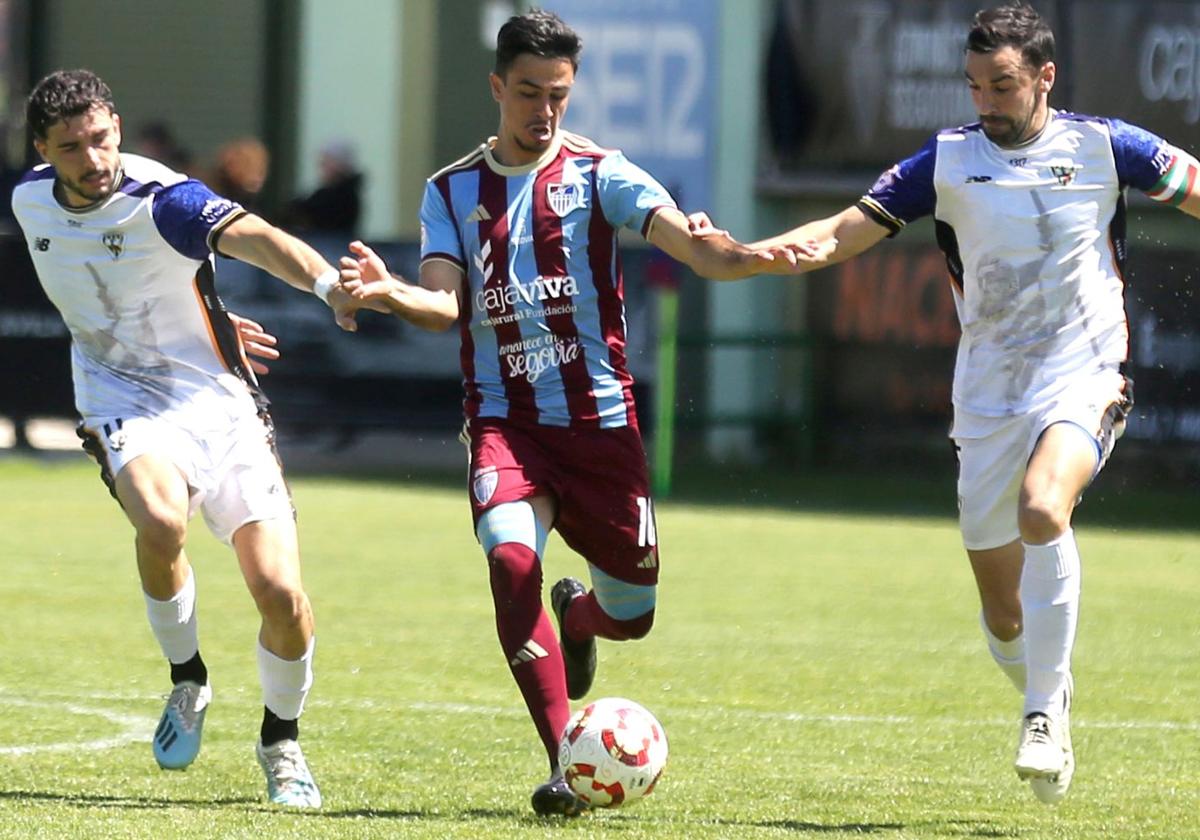 Javi Borrego conduce el balón ante dos defensores del Barakaldo.