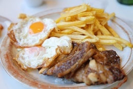 Segundo plato del menú, churrasco de ternera con dos huevos y patatas.
