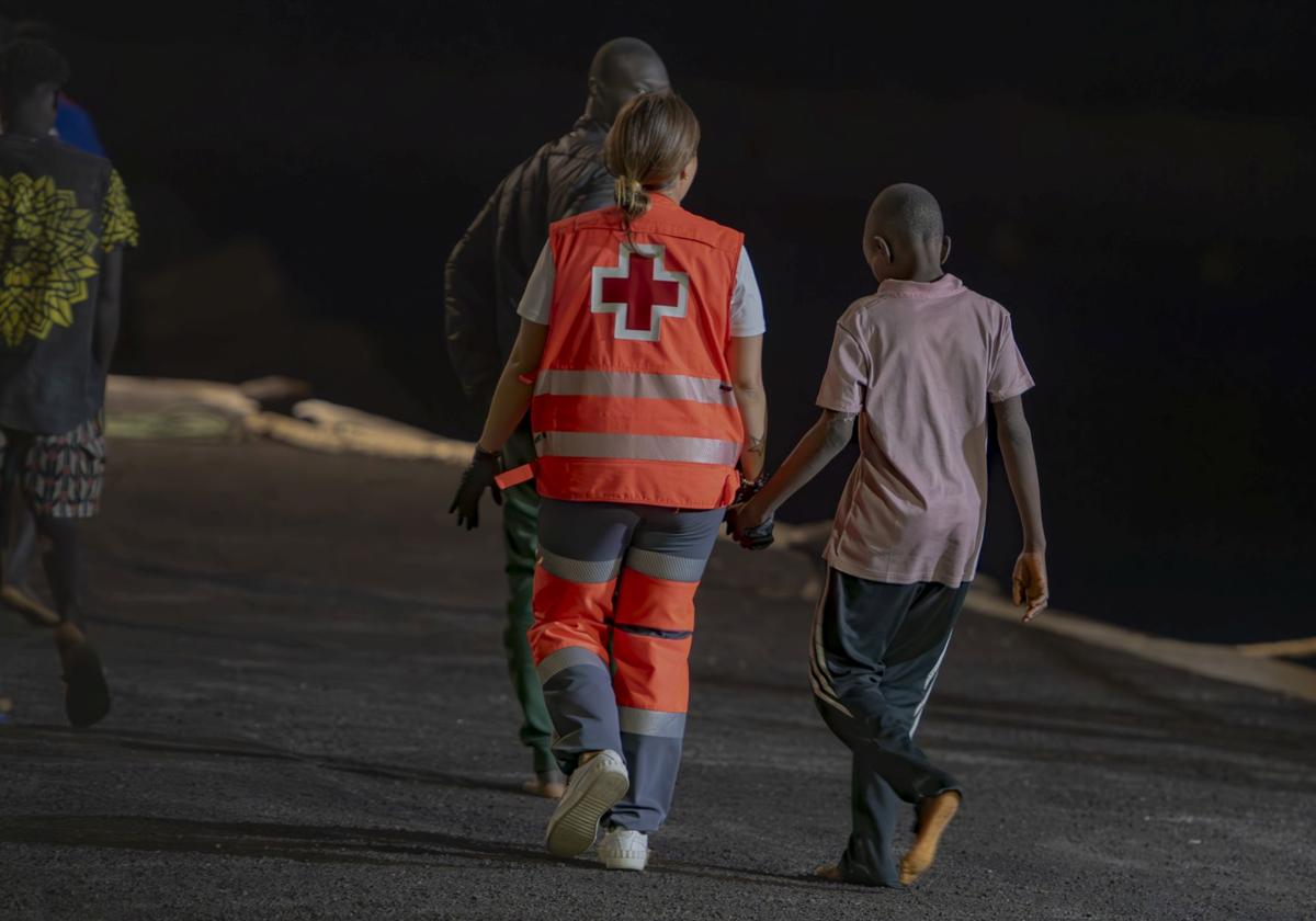 Un trabajador de la Cruz Roja atiende a un menor migrante que ha llegado al Puerto de La Restinga, en El Hierro.