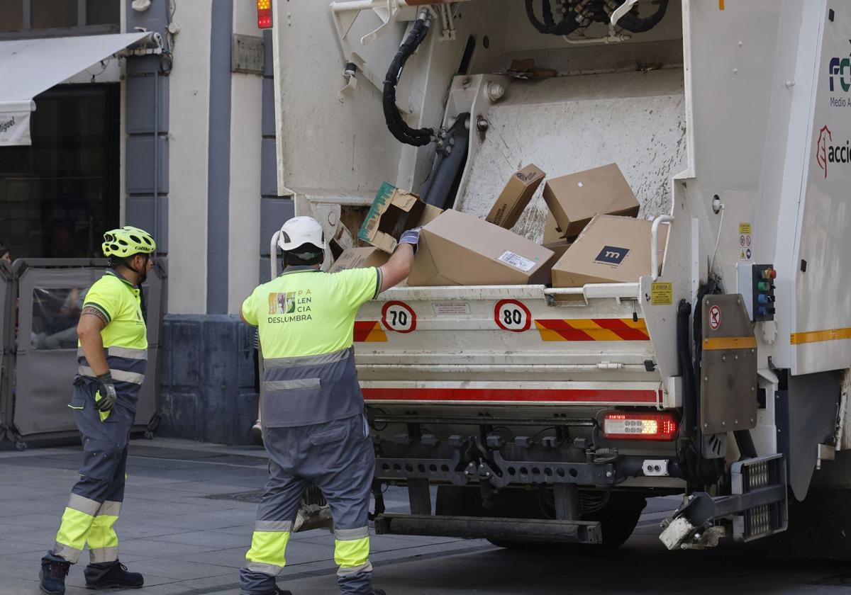 Operarios de Palencia Deslumbra recogen basura en la Calle Mayor.