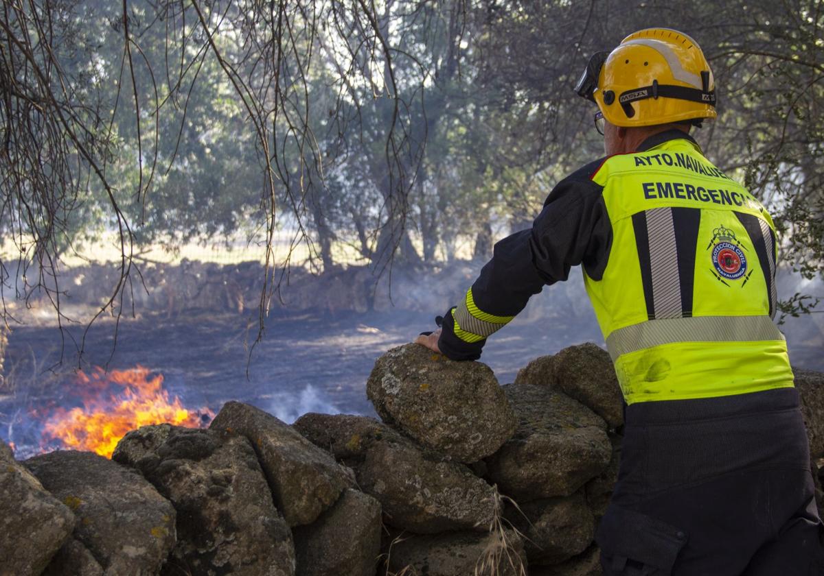 Un miembro de Protección Civil del Ayuntamiento de Navaluenga vigila una zona con llama.