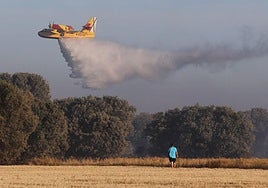 Una avioneta de la Junta esparce agua en la zona en llamas, en lo alto del valle de San Juan, junto al Monte.