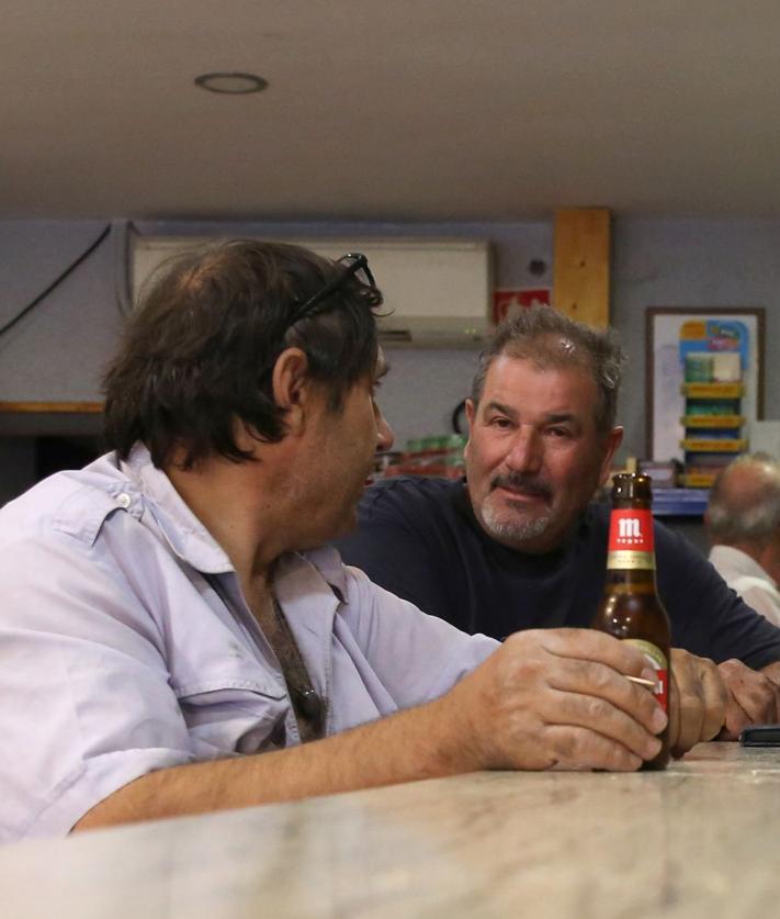 Imagen secundaria 2 - Arriba, dos mujeres, una española y otra extranjera, se abrazane n la terraza de un bar. Abajo algunos vecinos magrebíes charlan a las afueras del local, y a la izquierda, dos vecinos comparten una cerveza después del trabajo.