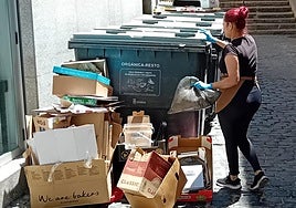 La trabajadora de un céntrico comercio de Segovia arroja residuos a un contenedor.