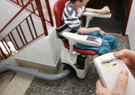 Un niño con parálisis cerebral, en una imagen de archivo, sube un tramo de escalera con un mecanismo adaptado.
