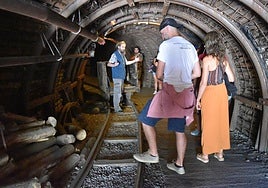 Varias personas atienden las explicaciones de un guía de la Mina Visitable.