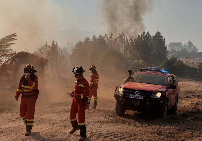 Los bomberos trabajan en la zona del fuego en medi de una intensa humareda.