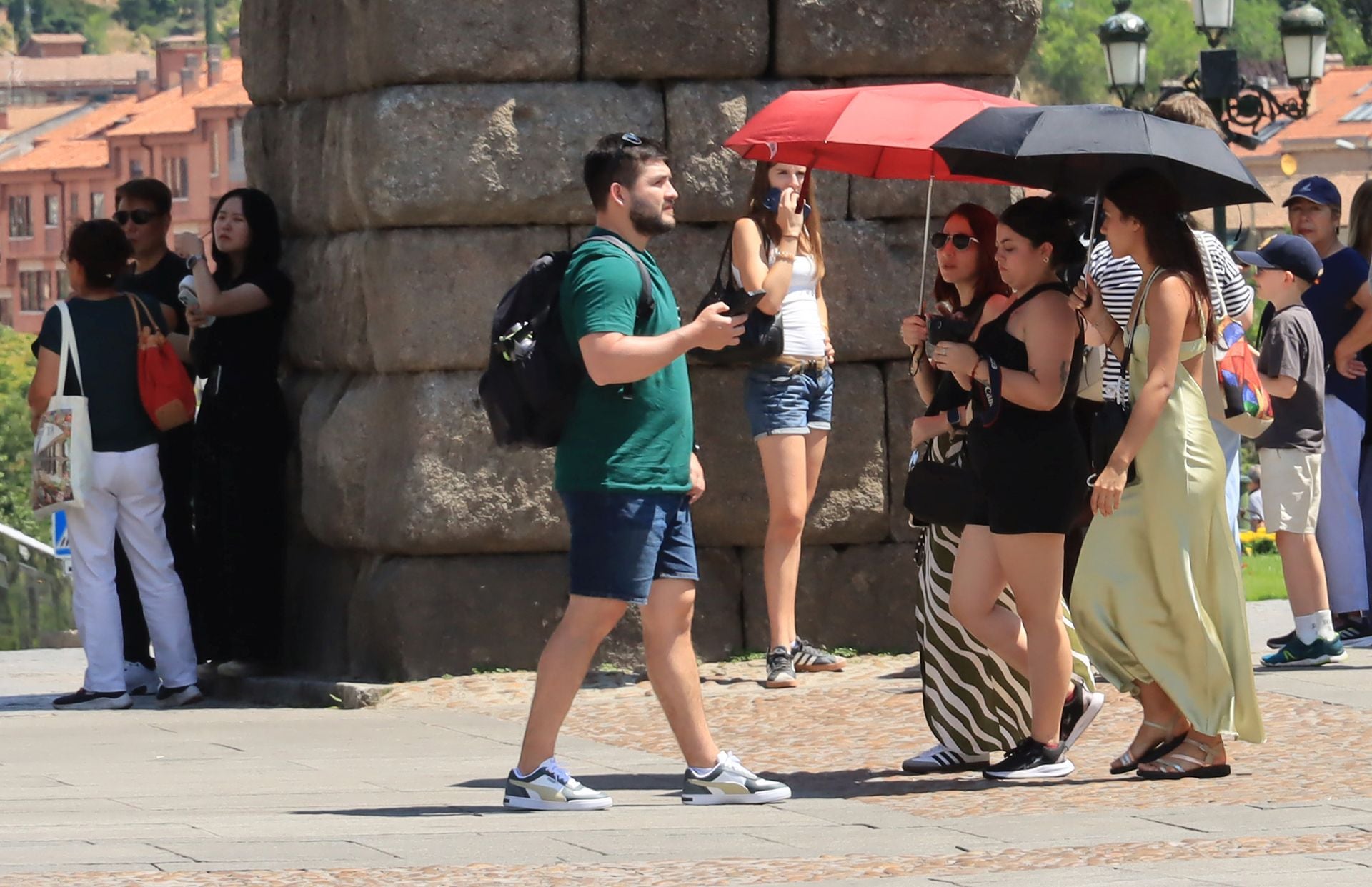 Tres chicas se protegen del sol en la plaza del Azoguejo este mes de julio.