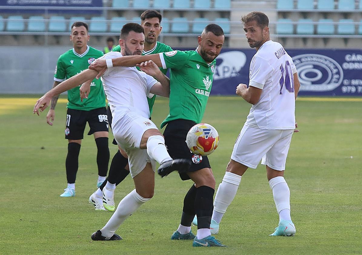 Iker Hernández intenta llevarse el balón ante Clavería, con Canario, que regresaba a La Balastera, atento a la acción.