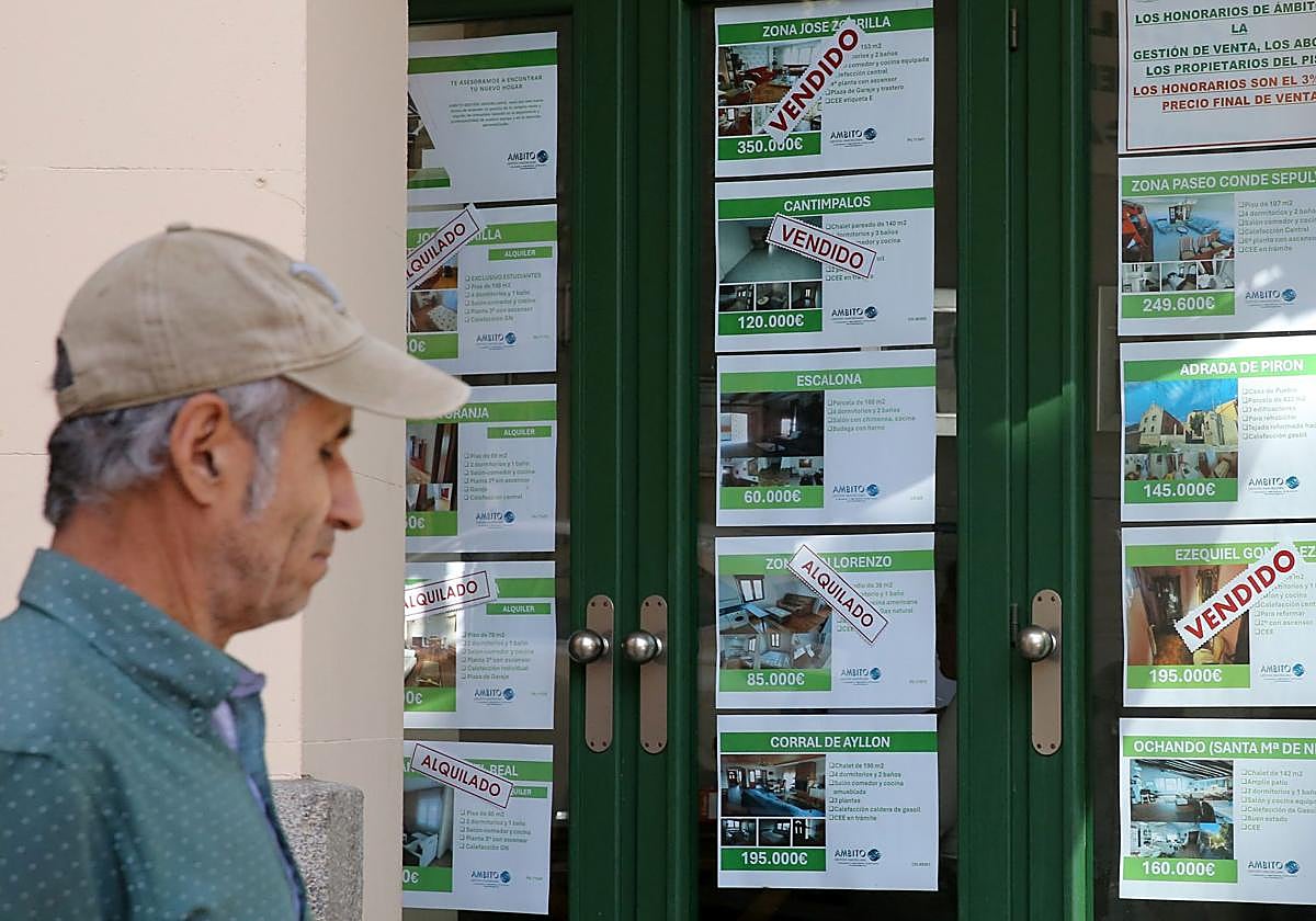 Un hombre pasa junto a los anuncios de un escaparate de una inmobiliaria en Segovia.