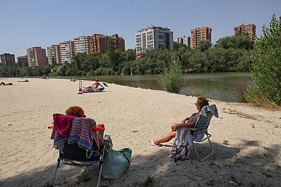 Dos amigas sentadas a la sombra en la playa fluvial de Las Moreras.
