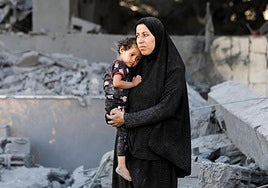 Una mujer palestina sostiene a un niño en las inmediaciones de una clínica evacuada de la UNRWA, tras un ataque israelí.