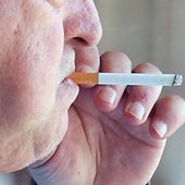 Un hombre fuma un cigarro por una calle de Segovia.