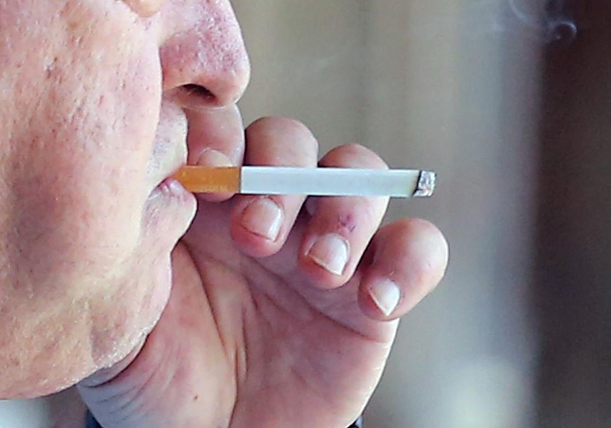 Un hombre fuma un cigarro por una calle de Segovia.