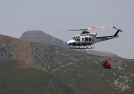 Un helicóptero del Gobierno lleva agua para extinguir el fuego, en la zona de Peña Carazo.