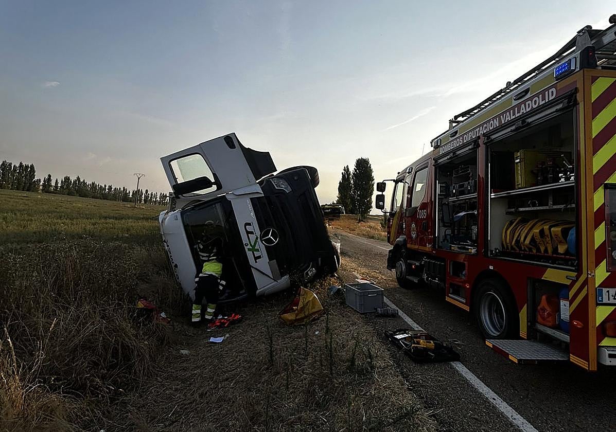 Los bomberos ayudan al conductor del camión tras el accidente.