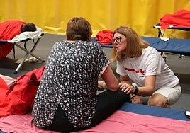 La psicóloga Montse Juanes se interesa por una mujer evacuada al Pabellón de Saldaña por los incendios.