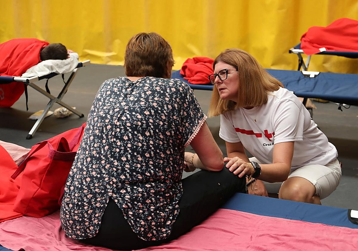 La psicóloga Montse Juanes se interesa por una mujer evacuada al Pabellón de Saldaña por los incendios.