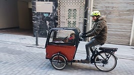 Daniel de Santiago lleva a un pasajero en la bicicleta de carga.
