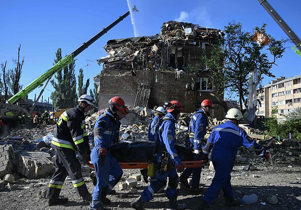 Rescatistas trasladan a una de las víctimas entre los escombros de uno de los edificios golpeados ayer por Rusia en Kiev.