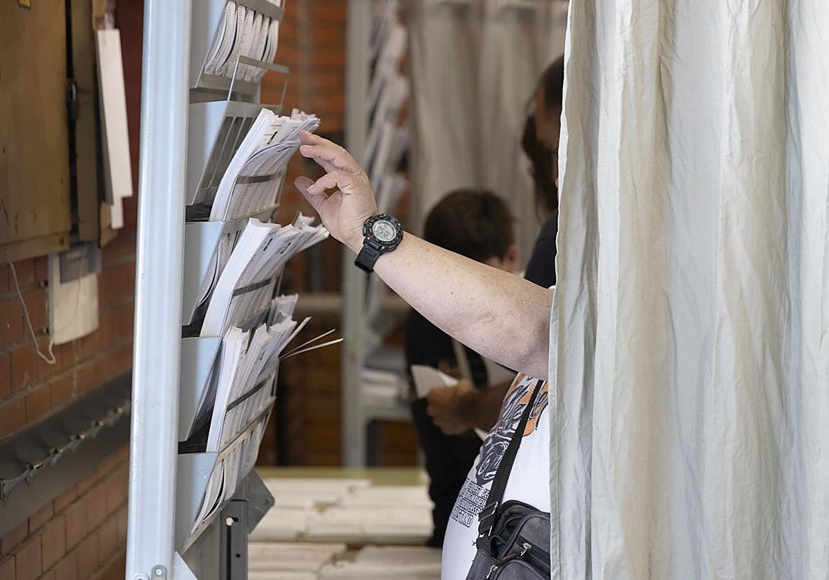 Una mujer escoge una papeleta durante unas elecciones.