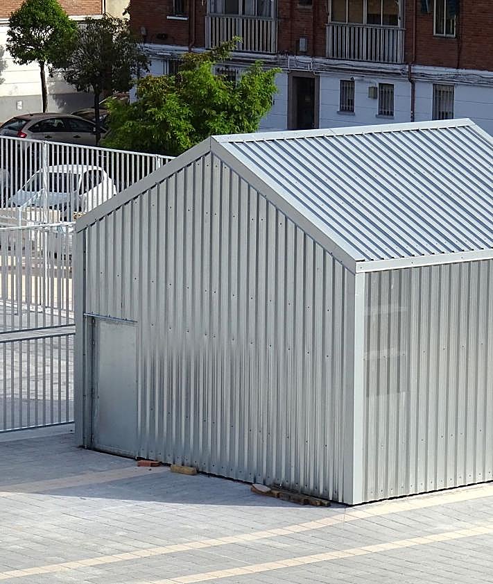 Imagen secundaria 2 - Estado de las obras entorno a la pista deportiva y detalle de la caseta forrada de chapa de acceso al ascensor del aparcamiento.