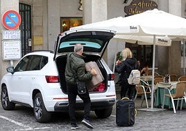 Una pareja de visitantes carga las maletas en un coche aparcado a las puertas de un hotel.