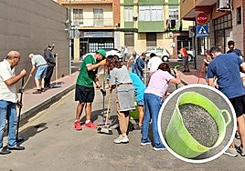 Los vecinos de la calle Sol, en plena faena el pasado sábado. En el círculo, un cubo lleno de la grava recogida.