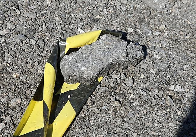 Una piedra sujeta la señalización que delimita las plazas en el aparcamiento provisional.