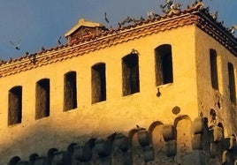 Decenas de palomas revolotean y se posan en el tejado del Torreón de Lozoya, en Segovia.