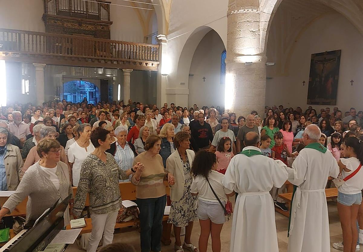 Los vecinos forman una cadena para darse la paz en la misa del viernes por la tarde en Saldaña.