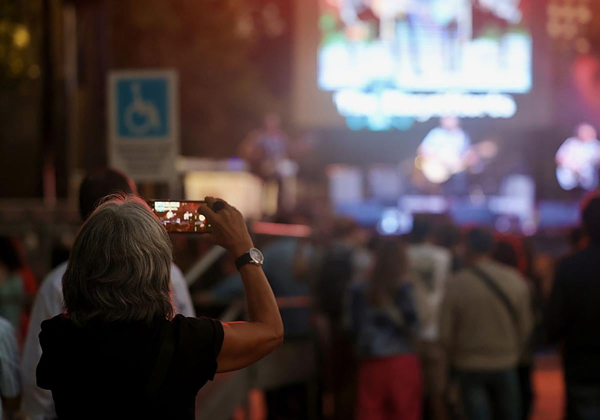 Una mujer graba con su móvil una actuación musical en Las Moreras, lugar de uno de los hurtos.