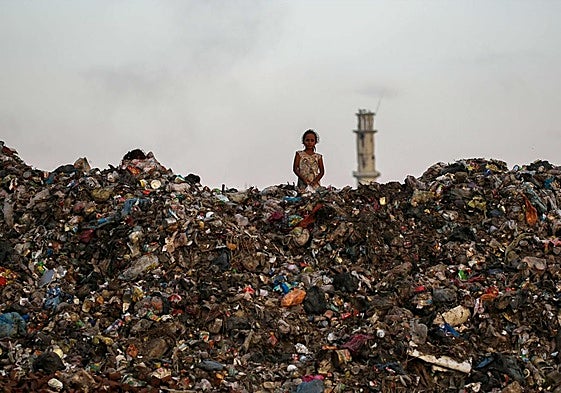 Una niña entre una montaña de escombros y basura en Gaza.