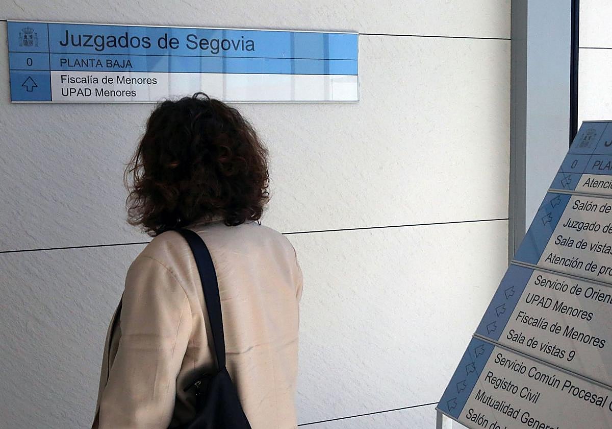 Una mujer observa el cartel que indica el acceso al Juzgado de Menores de Segovia.