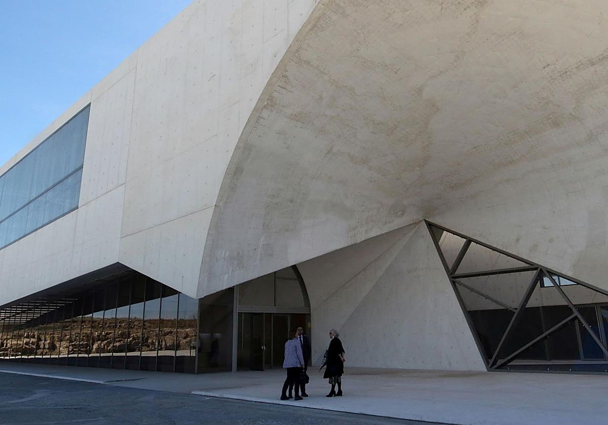 Un grupo de personas espera junto a la puerta principal de acceso del edificio CIDE, ubicado a las afueras de la ciudad.