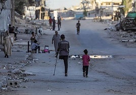 Un hombre palestino amputado camina con su hija por la calle Al Jalaa durante una operación militar israelí en la ciudad de Gaza.