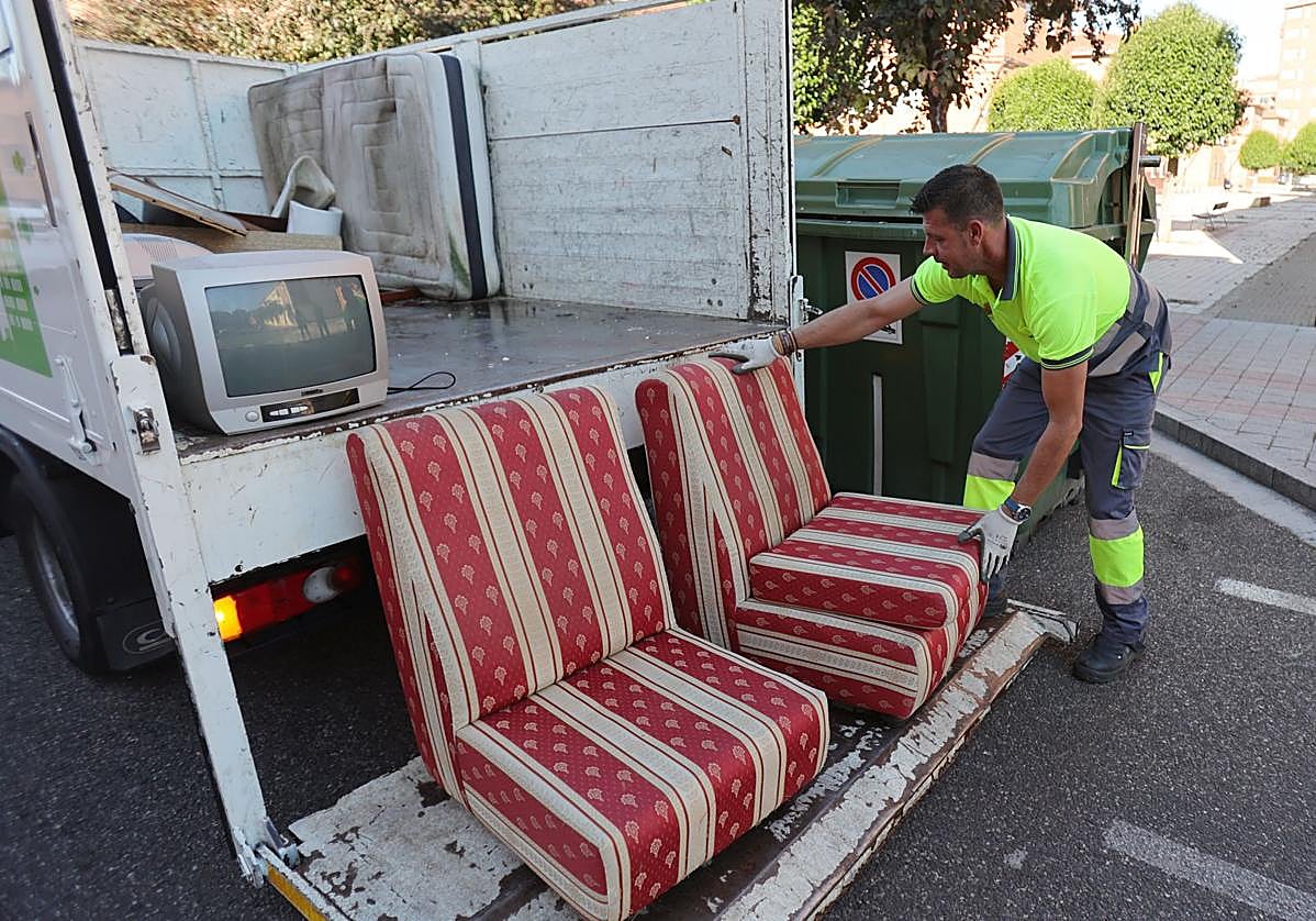 Un operario de Palencia Deslumbra recoge dos sillones abandonados.