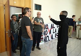 Un hombre con la cara tapada se dirige a algunos de los activistas en Derecho.