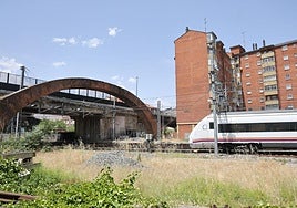 El tren pasa bajo el arco de ladrillo.