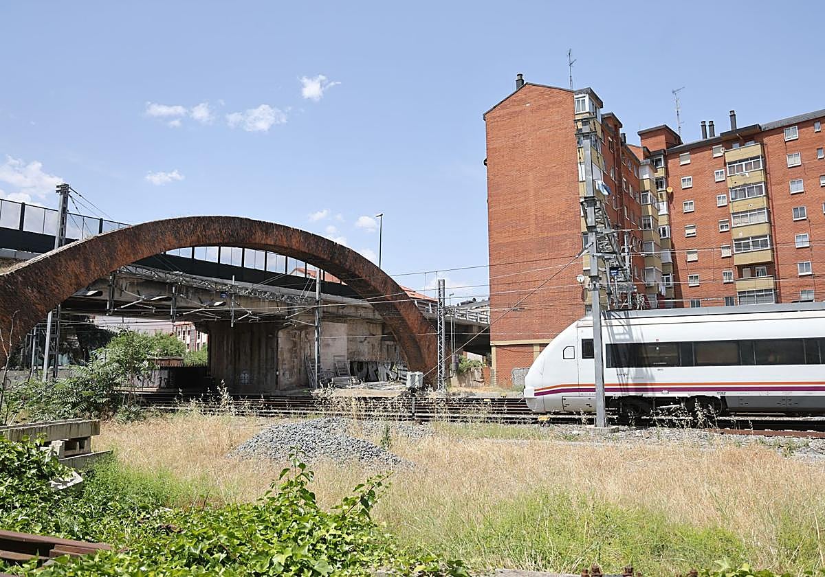 El tren pasa bajo el arco de ladrillo.