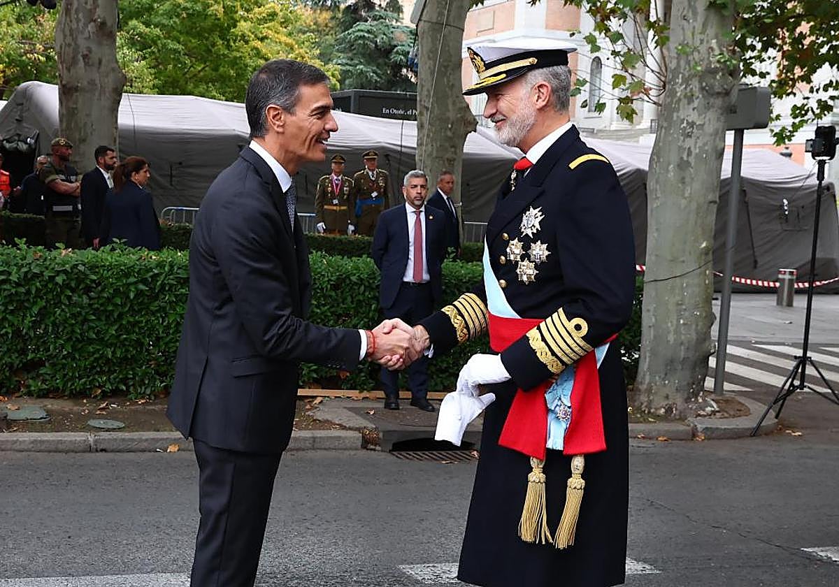 El rey Felipe VI (d) saluda al presidente del Gobierno Pedro Sánchez a su llegada al desfile de las Fuerzas Armadas con motivo de la Fiesta Nacional.