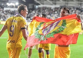 Iván Alejo sostiene una bandera de España con el escudo del Real Valladolid en presencia de Juanmi Latasa tras la victoria del Pucela en Burgos